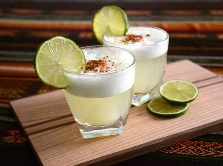 Two Pisco Sour cocktails standing on a table in a Peruvian restaurant with handmade tablecloth