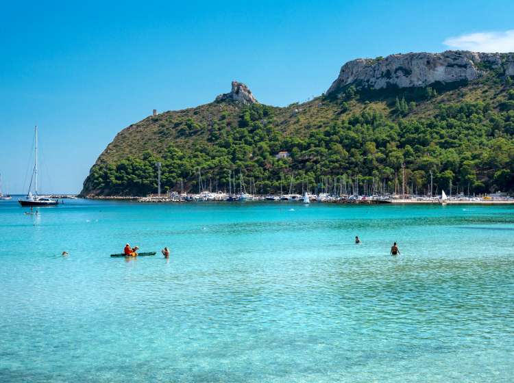 Poetto beach, crystal clear water and the famous Sella del Diavolo, Cagliari, Sardinia, Italy