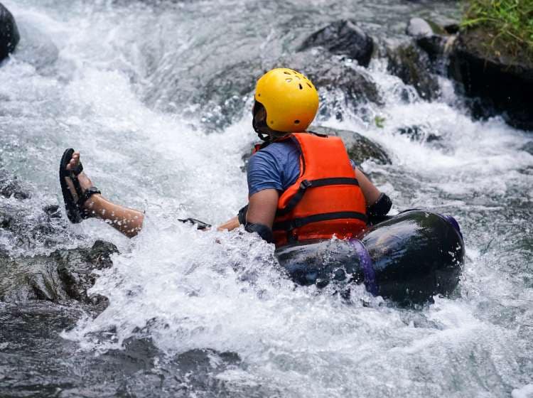 Man floating down a river stream in a blow up tube ; Shutterstock ID 1096609352; Invoice Number: -