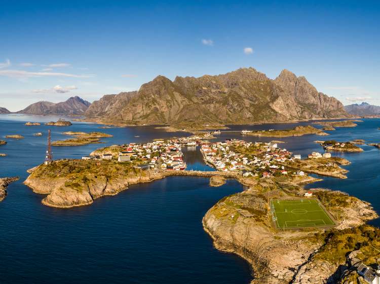 Aerial view of Henningsvaer, its scenic football field and mountains in the background. Henningsvaer is a fishing village located on several small islands in the Lofoten archipelago in Norway; Shutterstock ID 755564068; Invoice Number: -