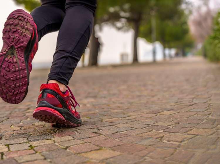 Close-up of a jogger's sneaker during a run in a park next to the sea.