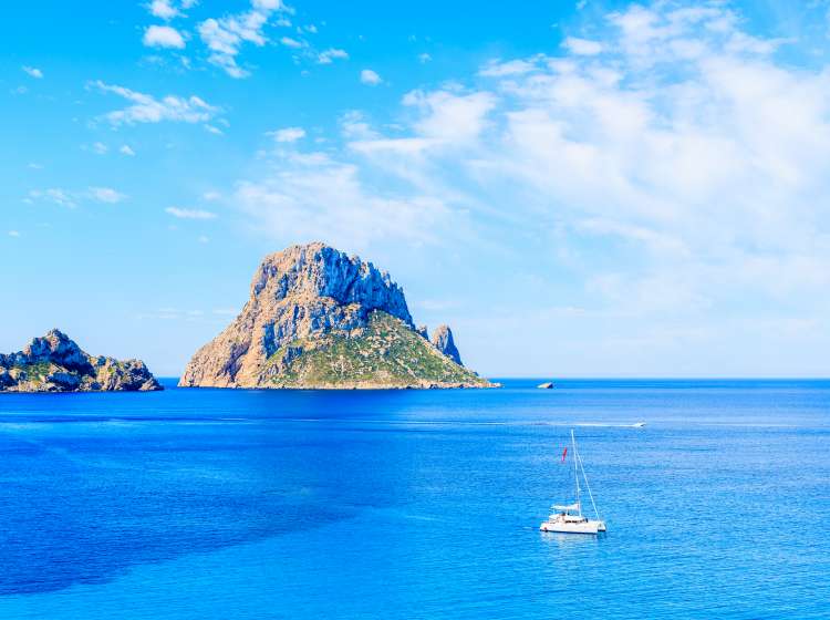 View of Es Vedra island and catamaran boat on blue sea in Cala d'Hort bay, Ibiza island, Spain; Shutterstock ID 648392947; Invoice Number: -