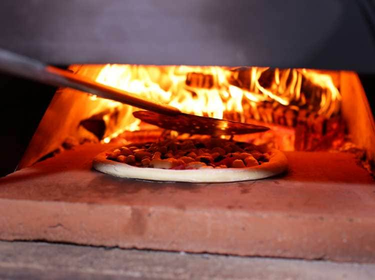 A pizza in a wood fired oven; Shutterstock ID 1062014630; Invoice Number: -