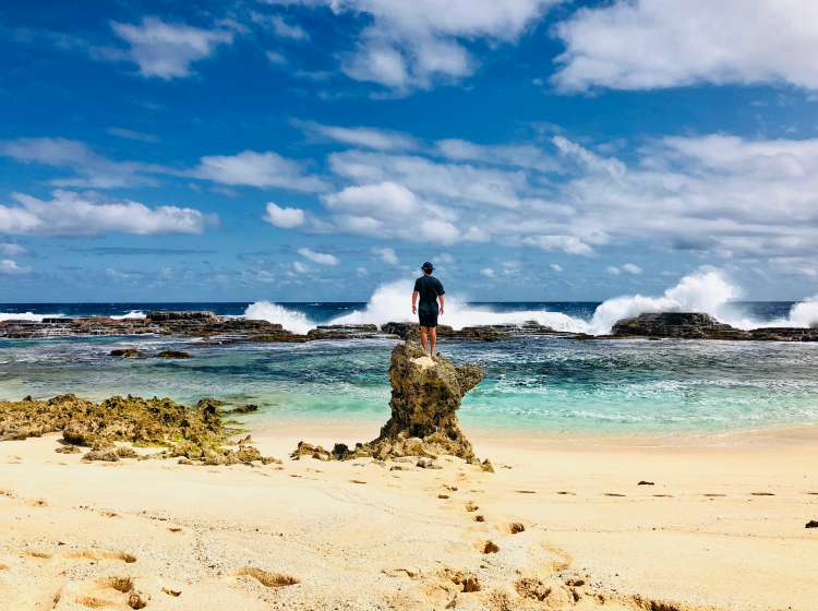 Rear view of man standing in the rock watching the waves breaking at rock pools in Tongatapu, Tonga, Pacific Islands