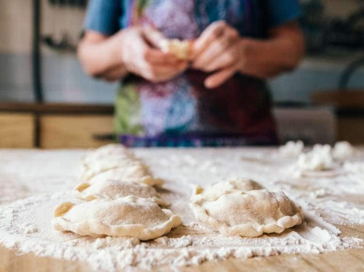 Aged woman preparing cookies filled with cottage cheese. Homemade bakery, traditional cuisine.