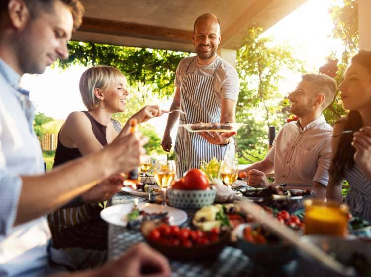 Caucasian male chef, serving to his friends a BBQ, during summer brunch in the garden