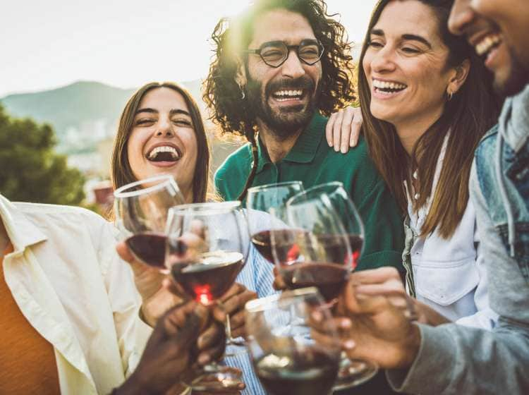 Happy friends toasting red wine glasses outside - Group of young people having bbq dinner party in backyard house - Winery and bbq dining concept with guys and girls cheering alcohol together