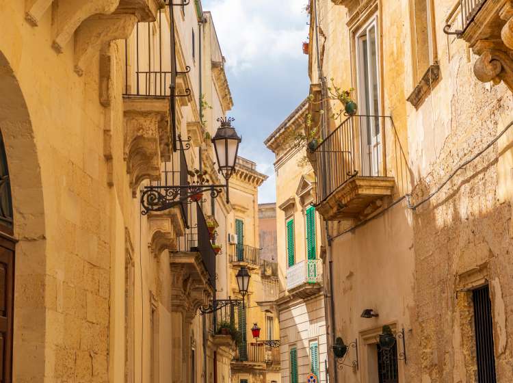 Italy, Apulia, Province of Lecce, Lecce. Stone buildings and iron balconies along a narrow street.