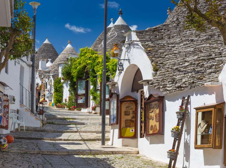 Beautiful town of Alberobello with trulli houses among green plants and flowers, main touristic district, Apulia region, Southern Italy