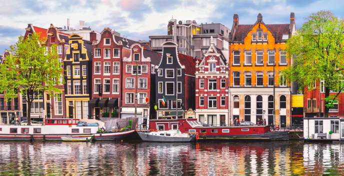  Boats in Amsterdam canal in front of buildings