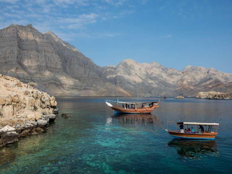 Boats in clear sea around mountain