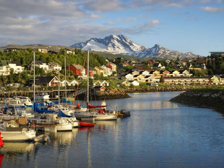 Boats on water infront of buildings and mountains