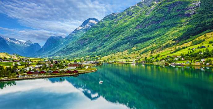  Big green mountains next to water and houses 