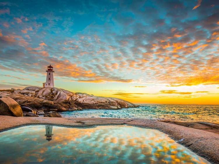 Lighthouse on beach shore whilst sun is setting