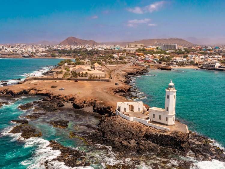 An aerial view of the shore of Praia de Santiago and the Praia lighthouse on a sunny day