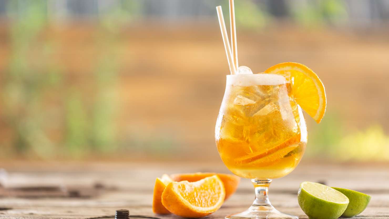 Beer lemonade with orange and ice on a garden table during a hot summer day.