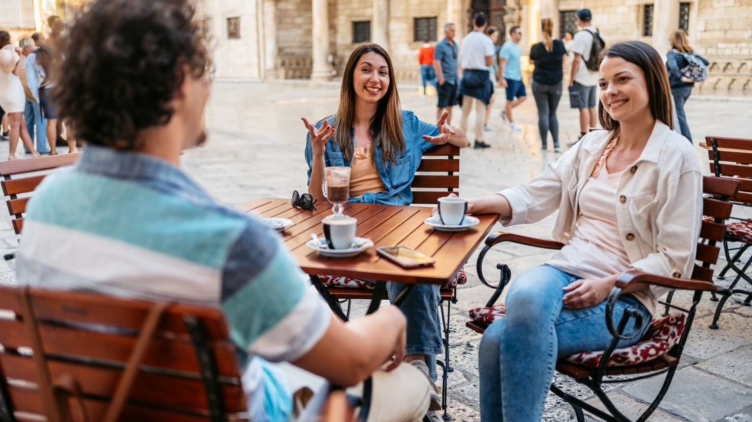 Three young friends drinking coffee in a sidewalk cafÃ© in Dubrovnik, Croatia.