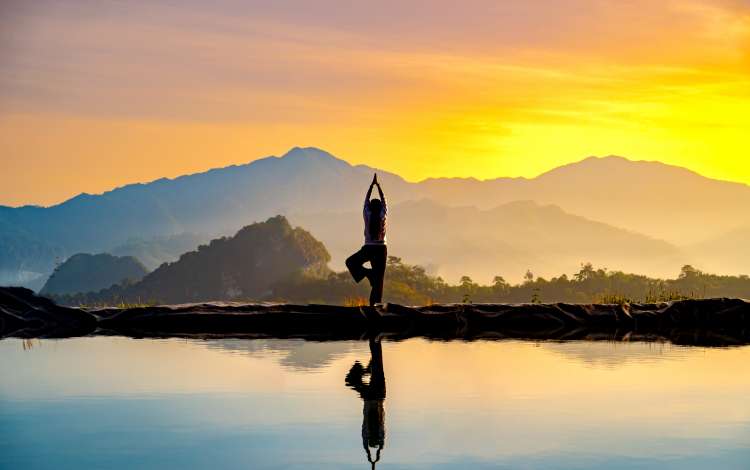 Woman practicing stretching On the high mountain slopes in the morning mist and by the reflection ponds