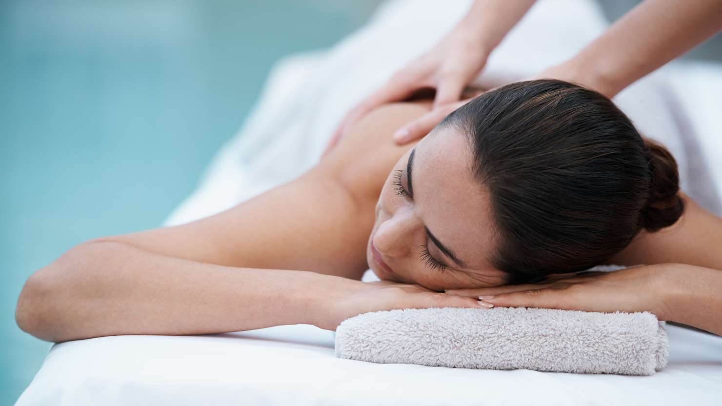 Cropped shot of an attractive woman enjoying a massage beside a pool at a spa