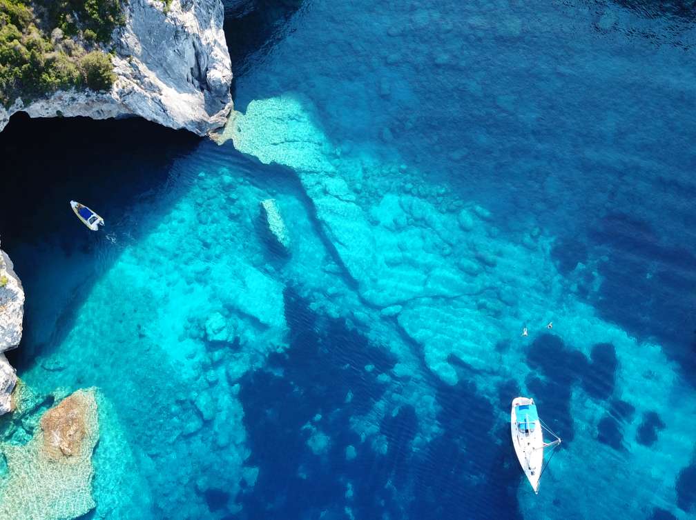 Aerial drone photo of sail boats anchored in tropical Caribbean island paradise bay with white rock caves and turquoise clear sea; Shutterstock ID 1166039707; project: olly; job: ; client: pocruises; other: 