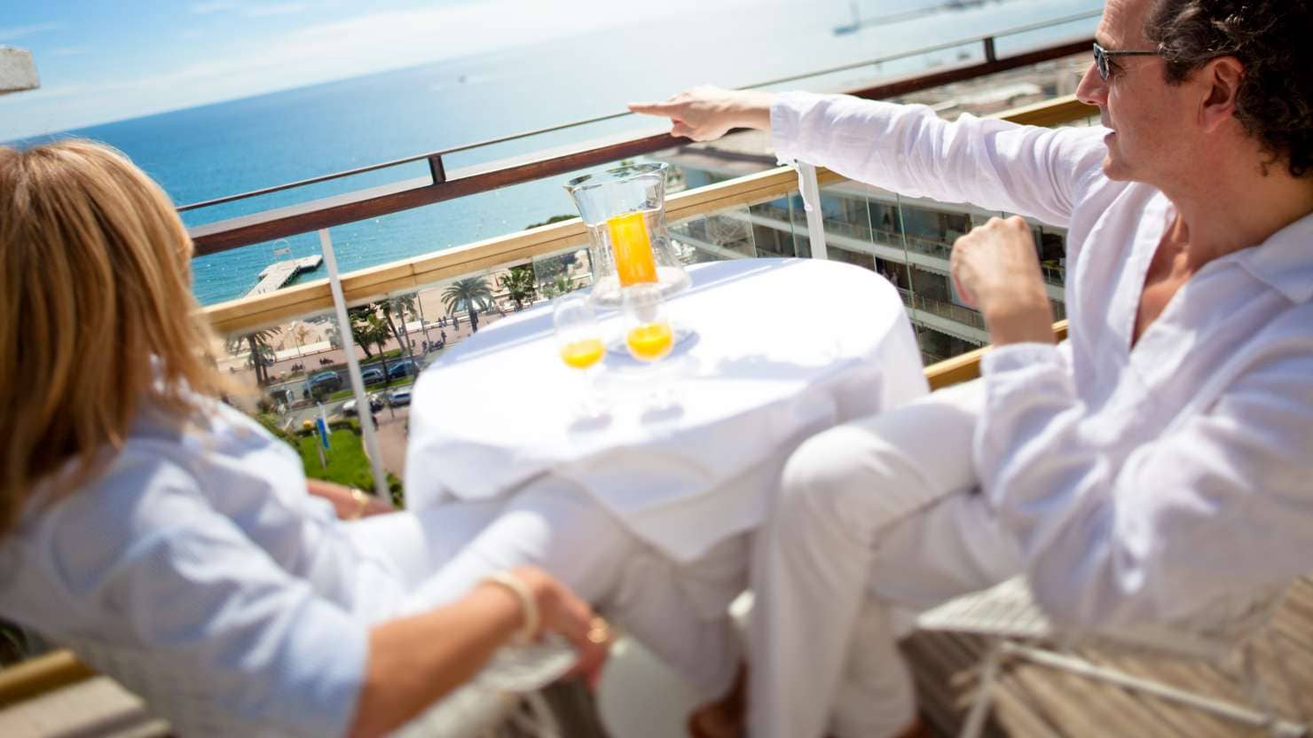 A happy middle aged couple relaxing and enjoying the view from a luxurious rooftop balcony in Cannes, France. Tilt shift lens with focus on people in foreground as well as the ocean in the distance.