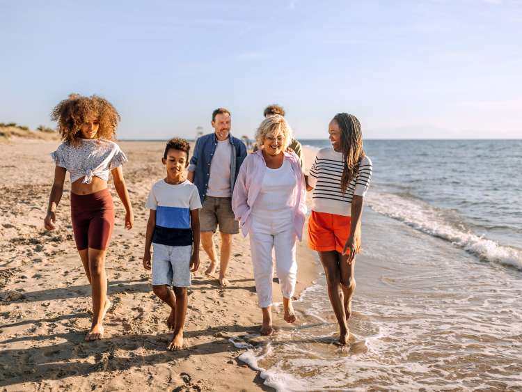 Multiracial family walking on the beach together, having fun and talking