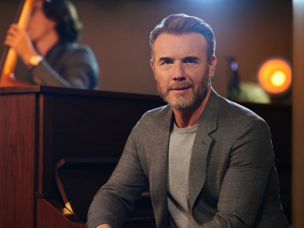 Gary Barlow sat at piano smiling