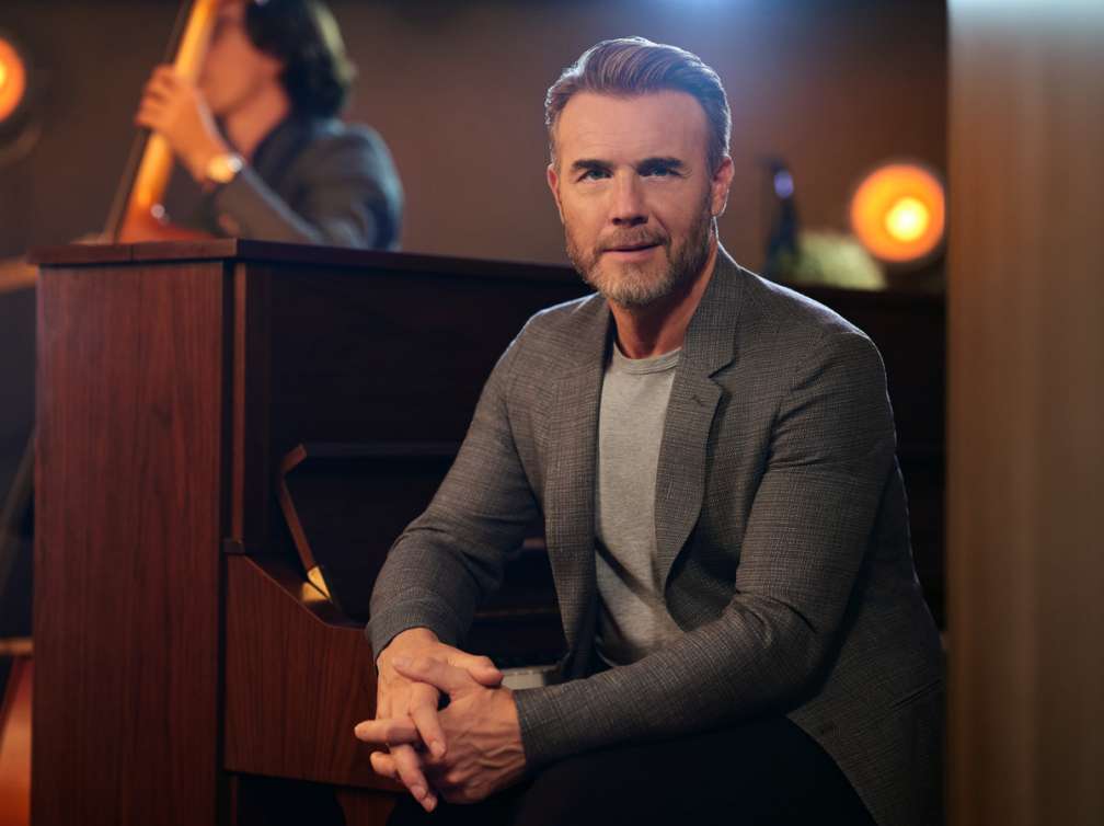 Gary Barlow sat at piano smiling