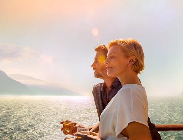  Couple drinking wine and looking out to sea on a sunny day 