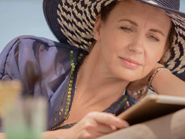  Lady in sun hat reading a book on deck