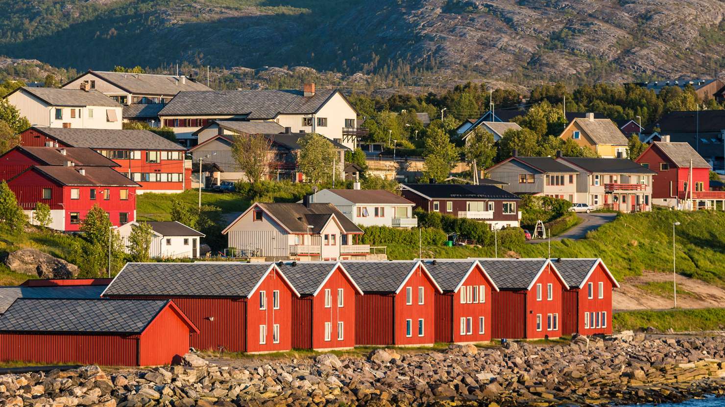 Red houses facades reflecting on the bay of Alta, Norway;