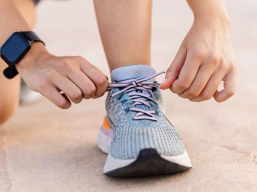 Close-up view of female jogger tying laces of her sport shoes before running exercise routine. Motivation, healthy lifestyle and fitness concept.