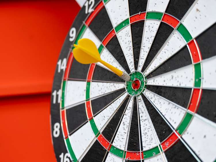 Dart arrow hitting in the target center of dartboard