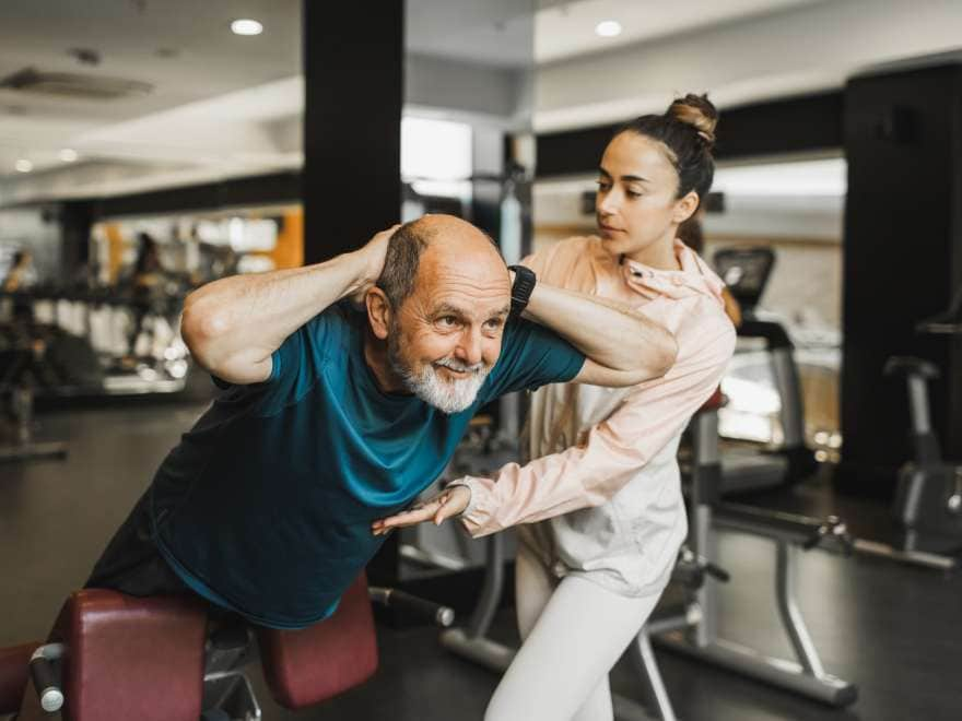 Healthy lifestyle on retirement. Body rehabilitation, training in gym. Senior adult man exercising with personal instructor. Active lifestyle of elderly people.