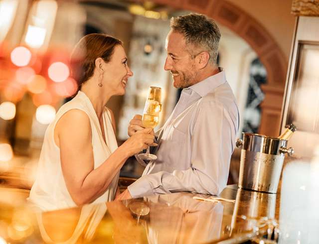 Couple chatting to each other holding drinks 