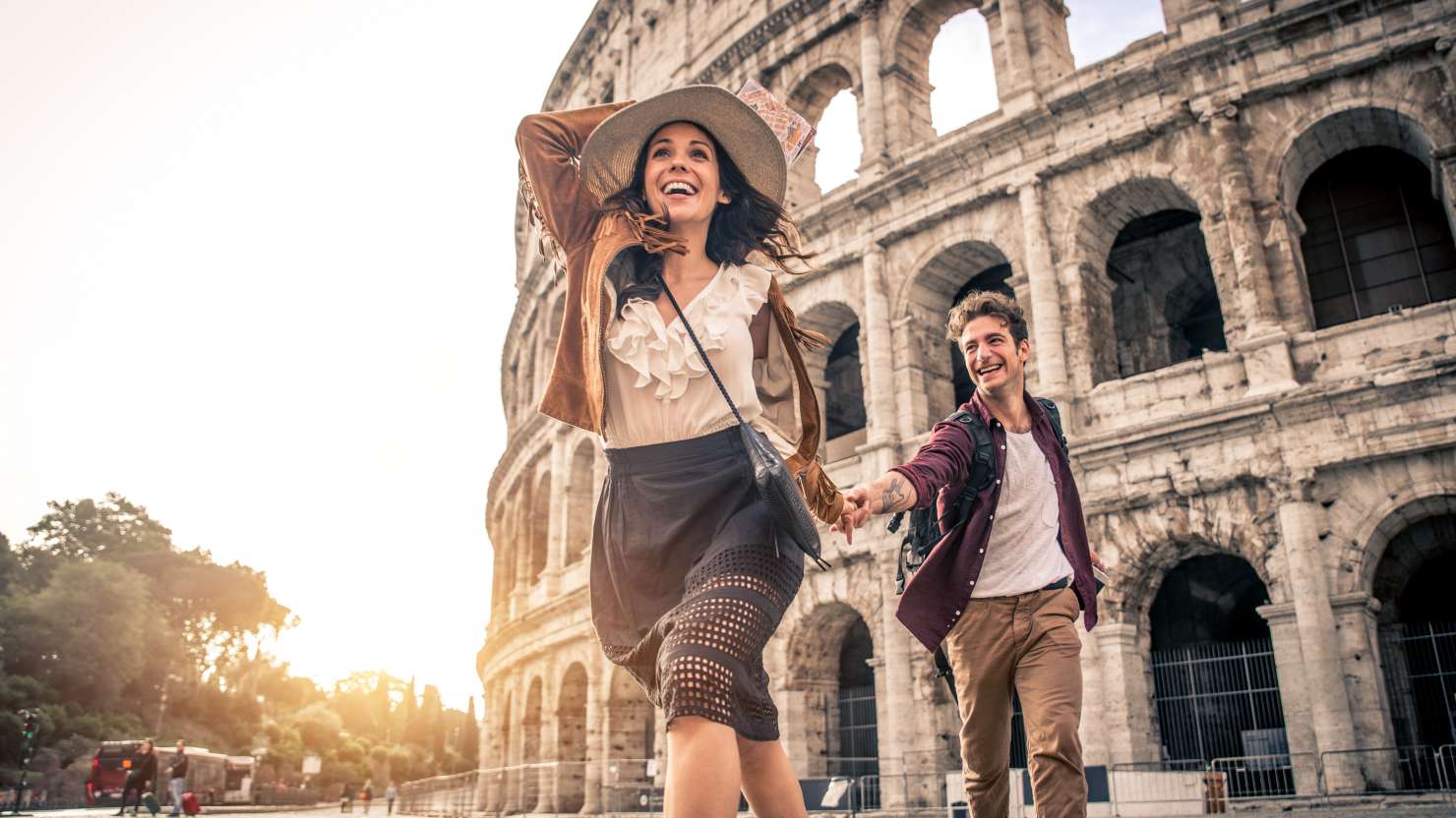 Young couple at the Colosseum, Rome - Happy tourists visiting Italian famous landmarks